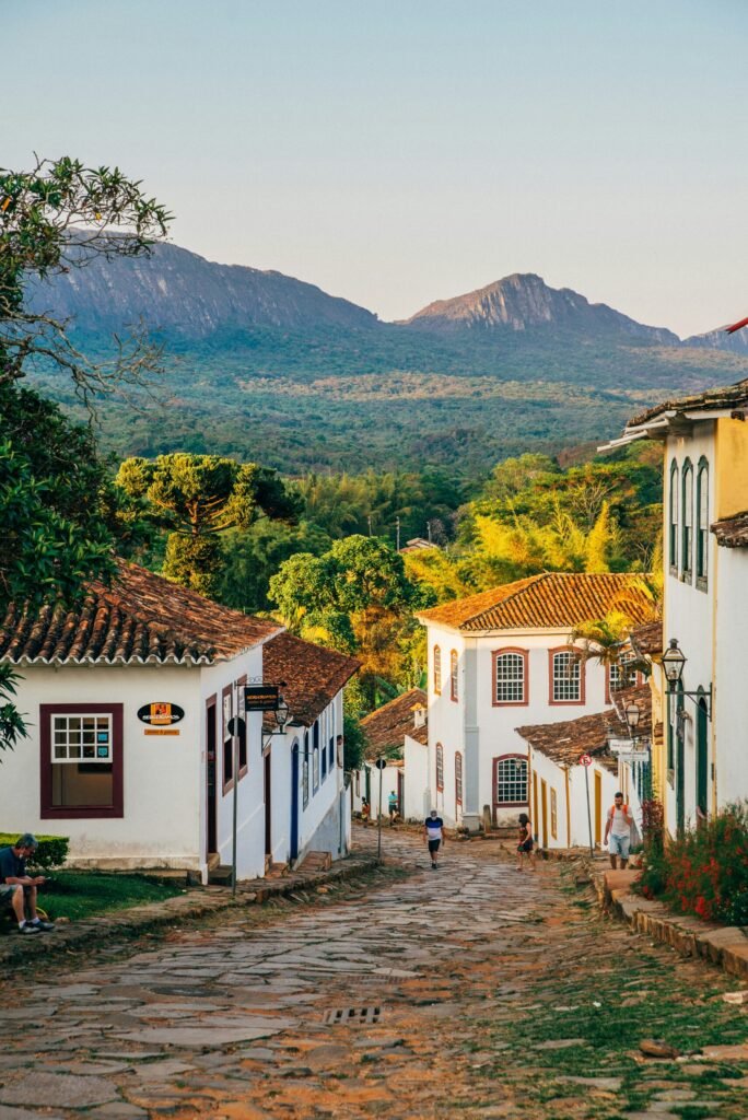 a cobblestone street with white buildings and mountains in the background a cobblestone street with white buildings and mountains in the background