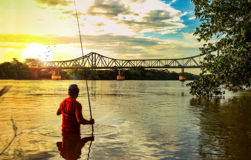a man fishing on a river with a bridge in the background a man fishing on a river with a bridge in the background