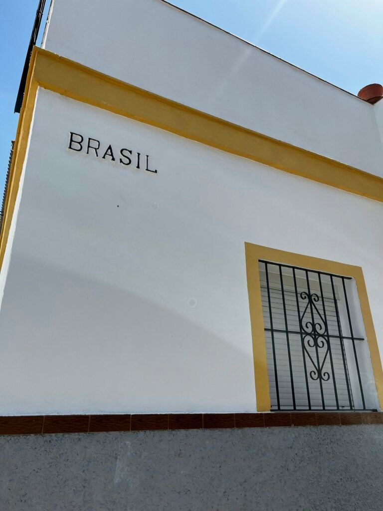 a white building with a yellow window and a wrought iron door a white building with a yellow window and a wrought iron door